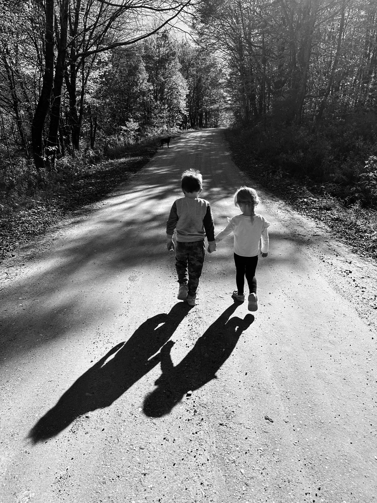 Image of two children walking down a road. 