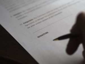 Image of someone signing a document. 